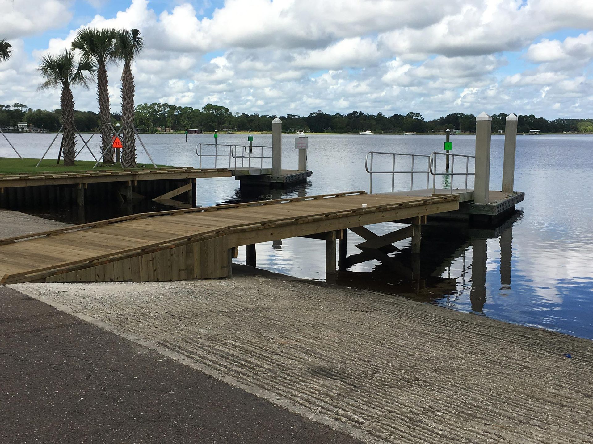 Boat ramp and dock on a lake with a cloudy sky in the background.