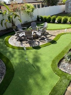 Backyard putting green with chairs around a fire pit.