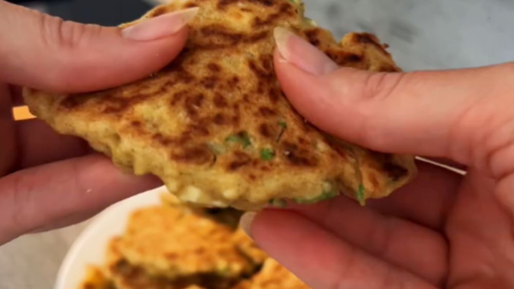 Eine Person hält ein Stück Essen in den Händen.