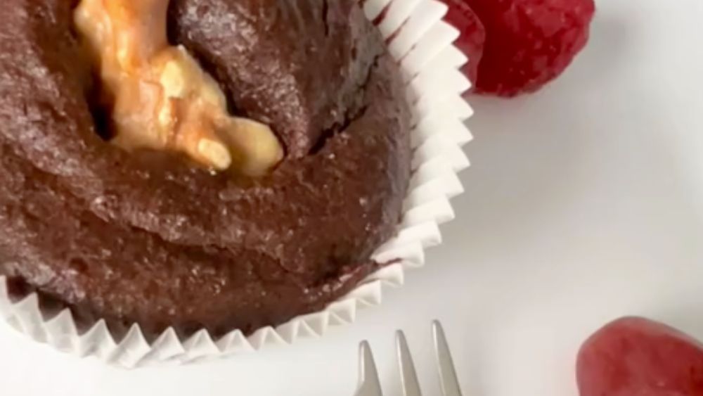 Eine Nahaufnahme eines Schokoladen-Cupcakes mit Himbeeren und einer Gabel.