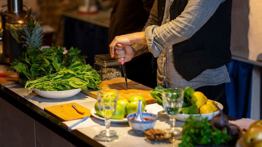Eine Frau schneidet in einer Küche Gemüse auf einem Schneidebrett.
