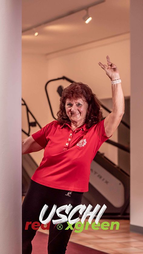 Eine Frau in einem roten Hemd tanzt in einem Fitnessstudio.