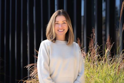 Taylor Archer smiling in front of a black fence
