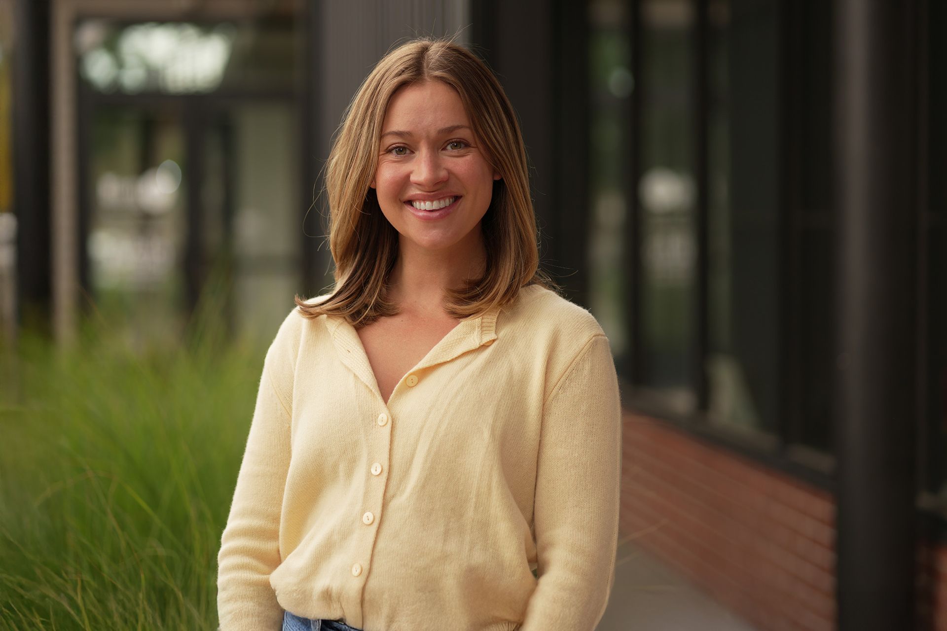Taylor Archer smiling outdoors, wearing a light sweater.