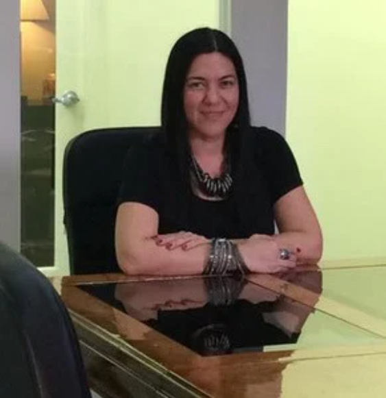 A woman is sitting at a table with her arms crossed.