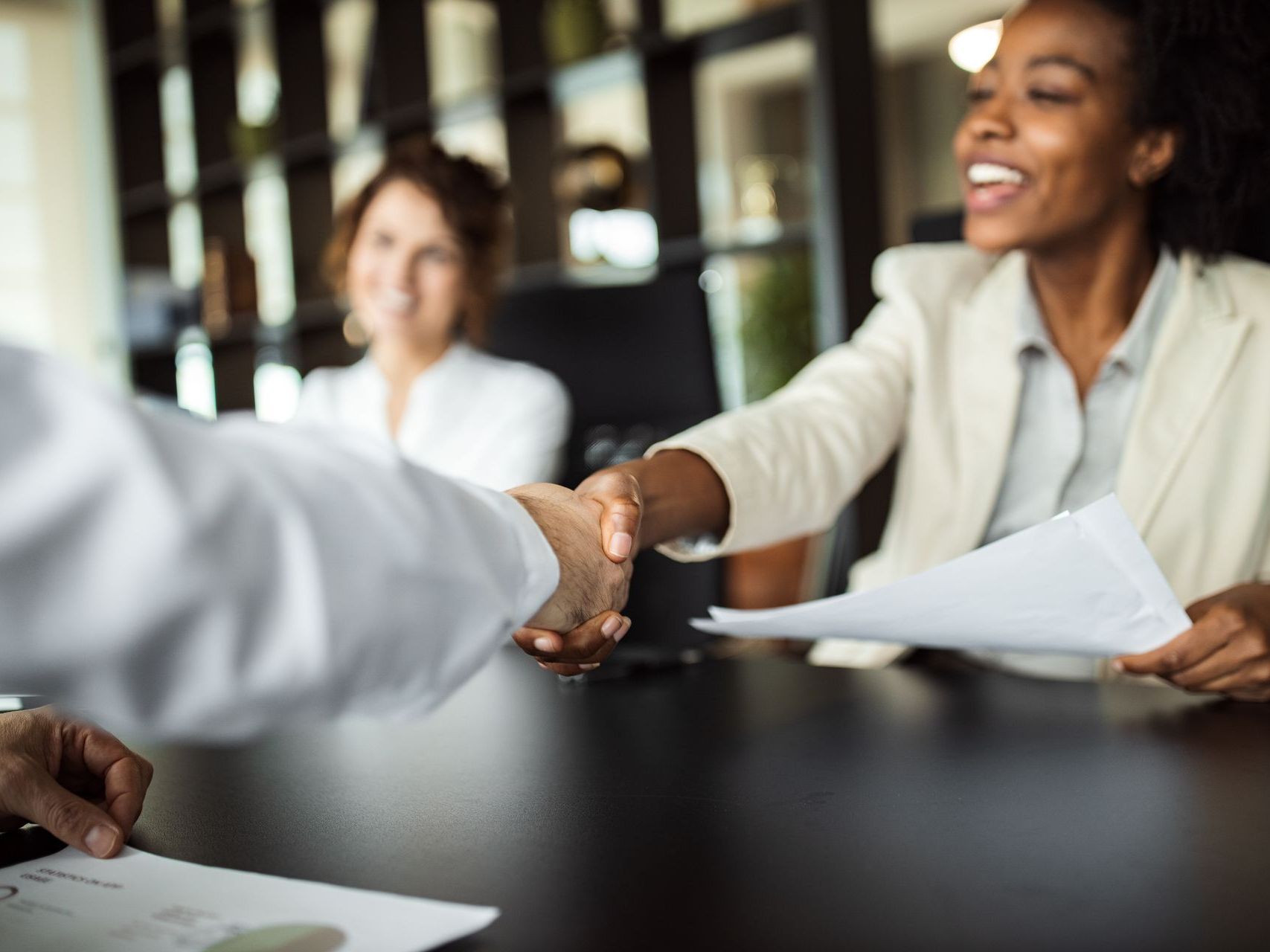 A woman is shaking hands with a man at a table.