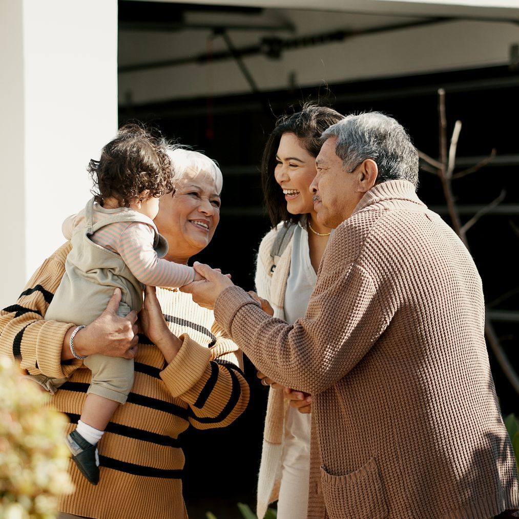 A woman is holding a baby while talking to two men