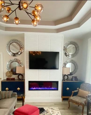 Modern living room with wall-mounted TV, electric fireplace, mirrored decor, and navy side cabinets