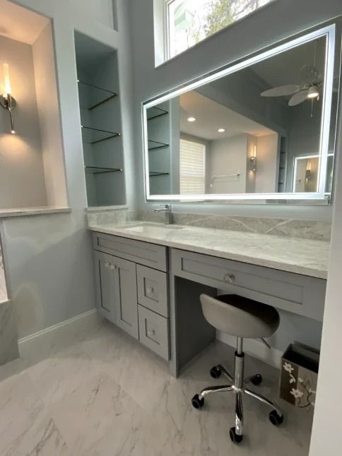 Modern gray bathroom vanity with large illuminated mirror and swivel stool