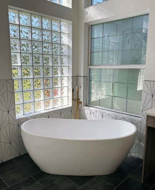 Modern bathroom with a freestanding white tub beside frosted and clear glass block windows.