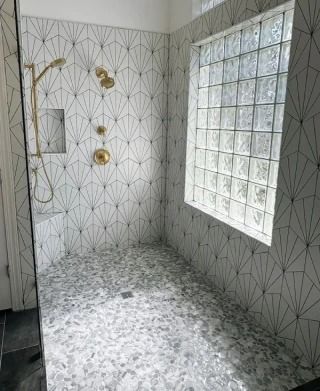 Modern bathroom with geometric tile, gold fixtures, and a large frosted glass window.