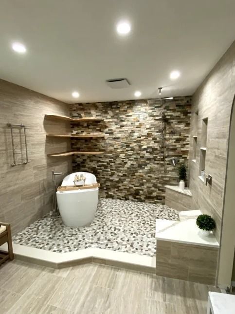 Modern bathroom with stone accent wall, white freestanding tub, mosaic tile floor, and recessed lighting