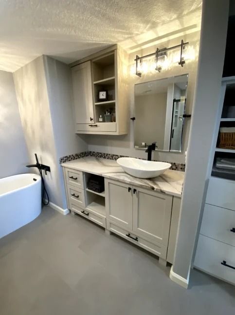 Modern bathroom vanity with mirror, white cabinetry, sink, and vanity lights beside a bathtub