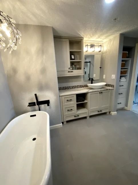 Bright bathroom with a freestanding tub, vanity, mirror, and built-in storage.