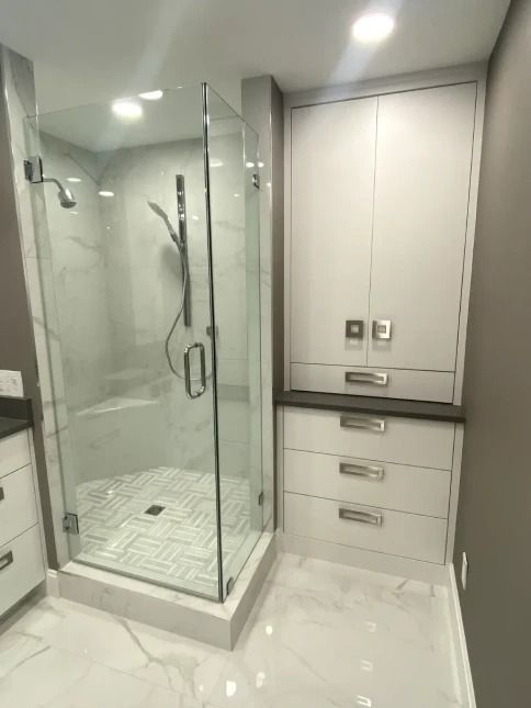 Modern bathroom with glass shower, white tile, and built-in vanity cabinets