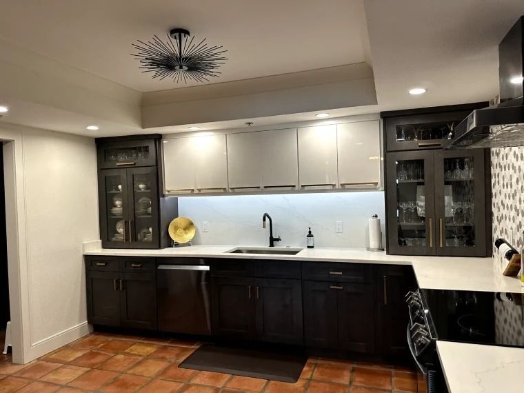 Modern kitchen with dark lower cabinets, white upper cabinets, and a white countertop under recessed lighting