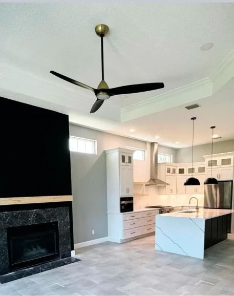 Modern open-concept kitchen and living room with black fireplace, island, pendant lights, and ceiling fan