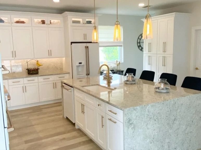 Bright white kitchen with marble island, pendant lights, and black barstools