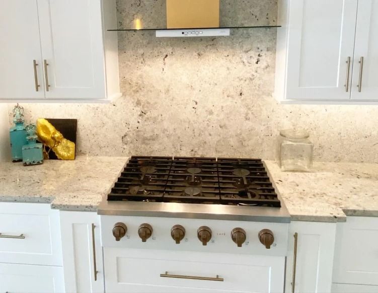 White kitchen with gas stovetop, marble backsplash, and white cabinets