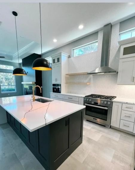 Modern kitchen with white cabinets, black island, marble countertops, and stainless steel appliances