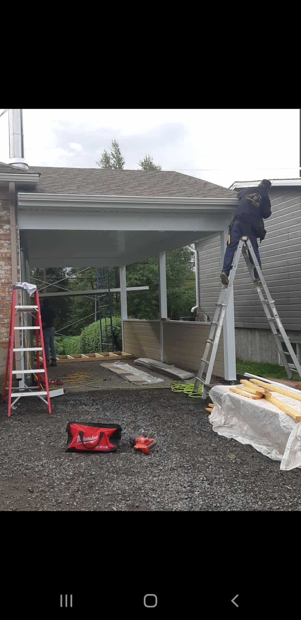 Ouvrier du bâtiment sur une échelle, travaillant sur la façade d'un bâtiment. Outils au sol.
