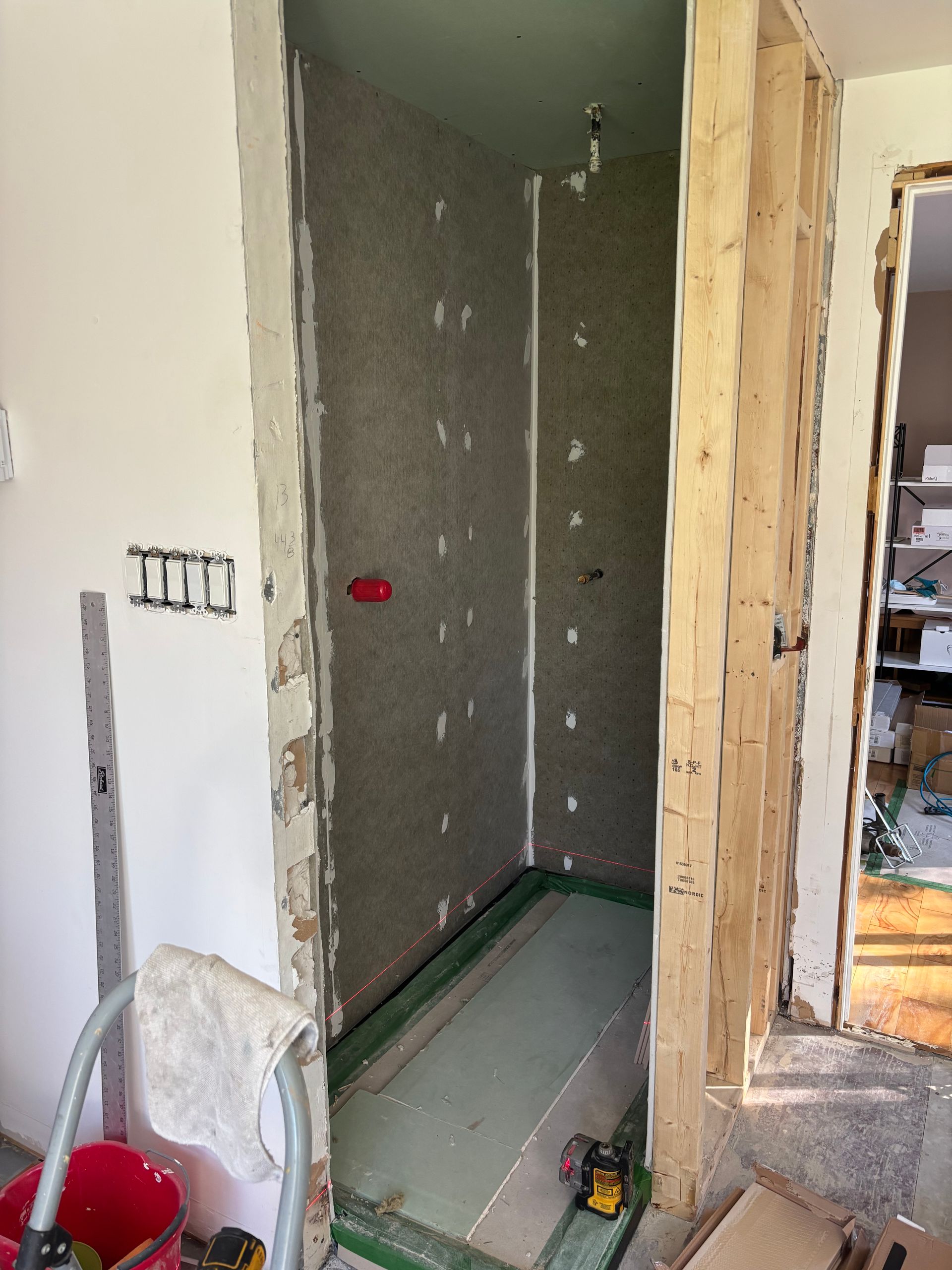 Rénovation de salle de bains en cours ; murs avec isolation apparente, base verte.