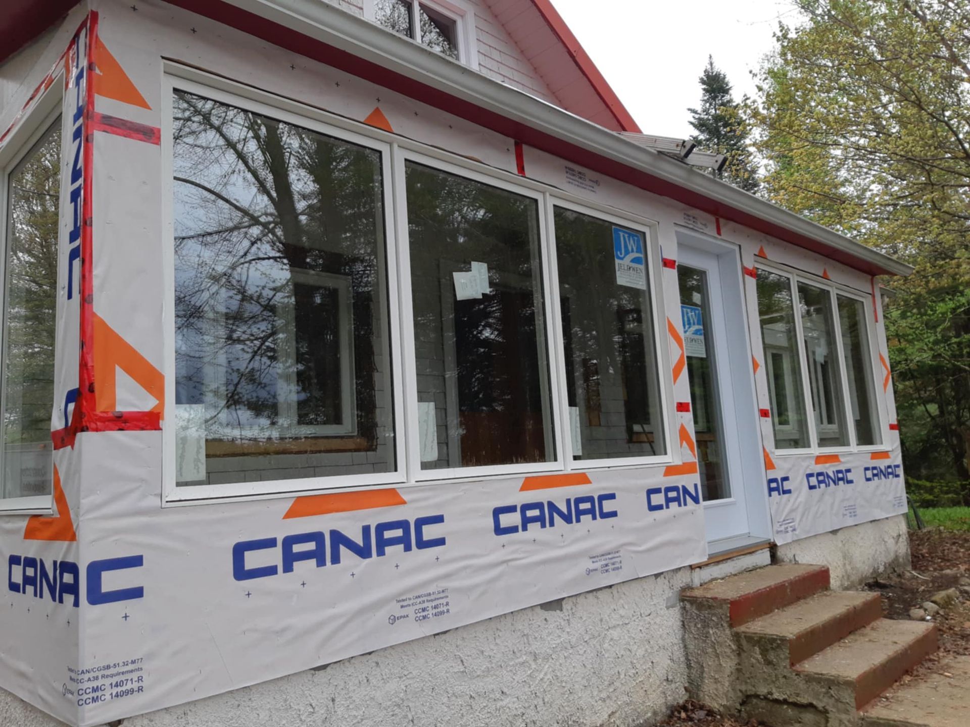 Extension de véranda avec de nouvelles fenêtres, construction en cours ; cadres blancs, revêtement bleu.