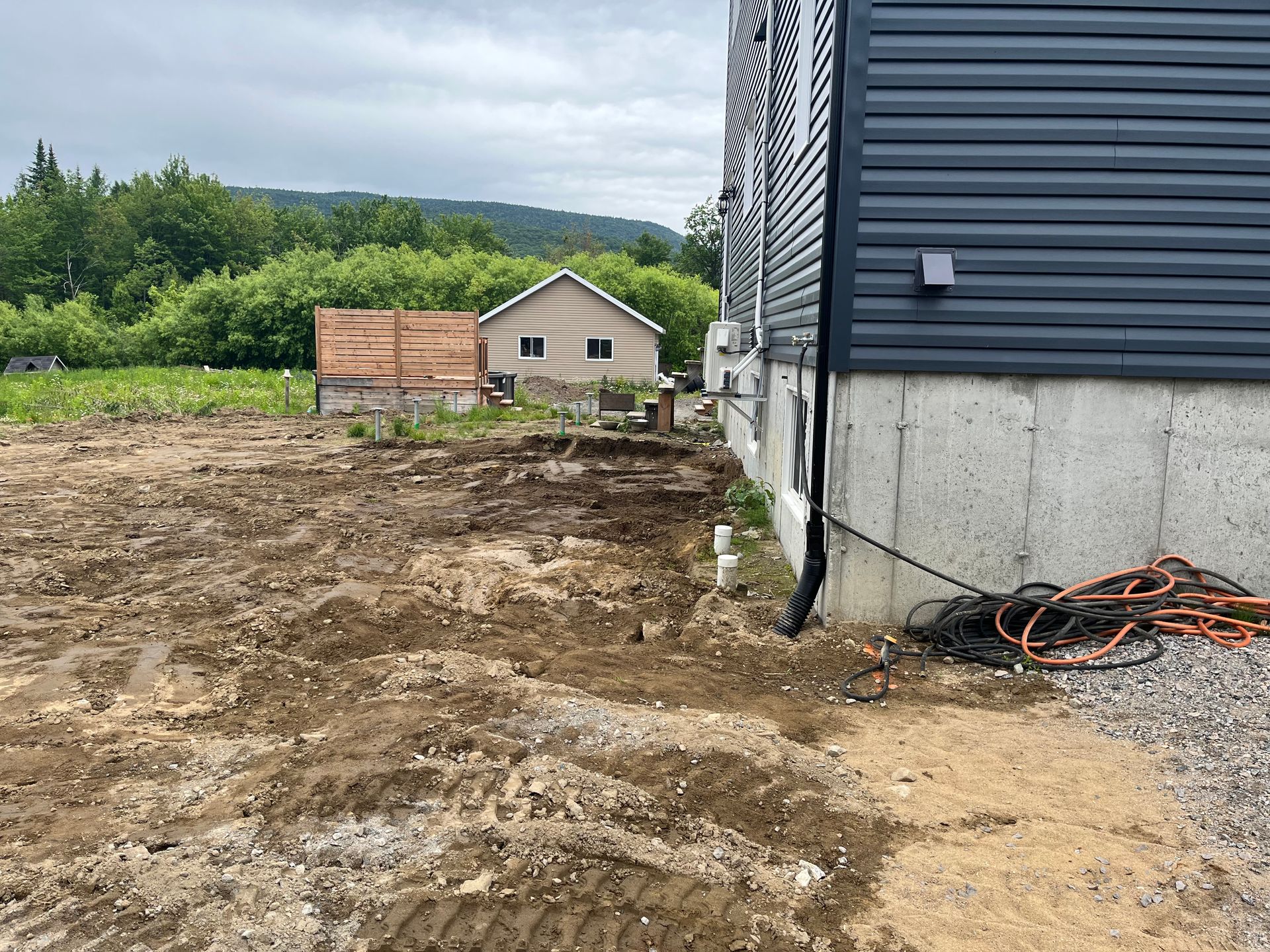 Vue extérieure d'un chantier de construction avec une maison partiellement construite et la terre environnante.