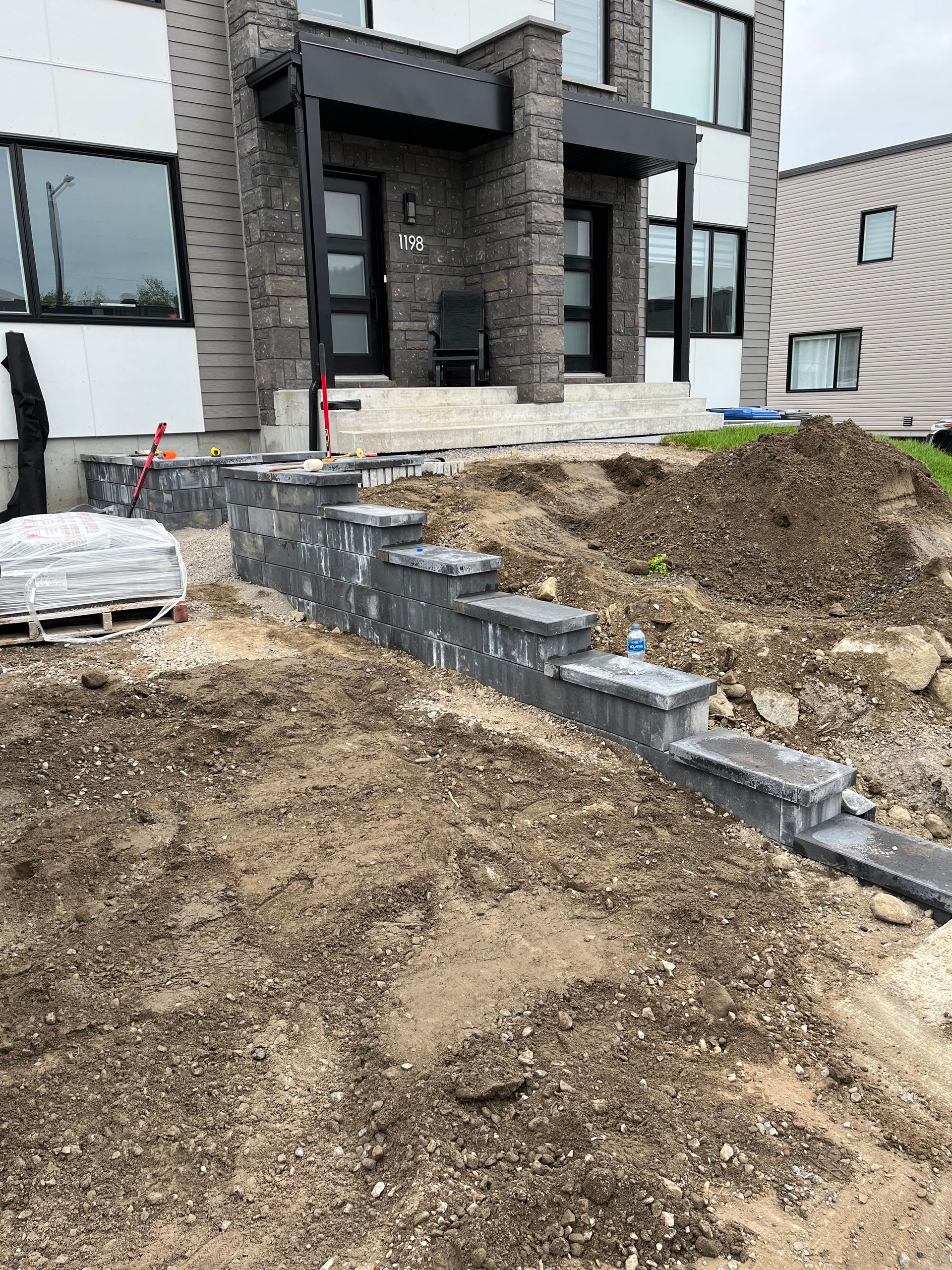 Vue extérieure d'un escalier en construction menant à un bâtiment moderne à la façade grise et blanche.