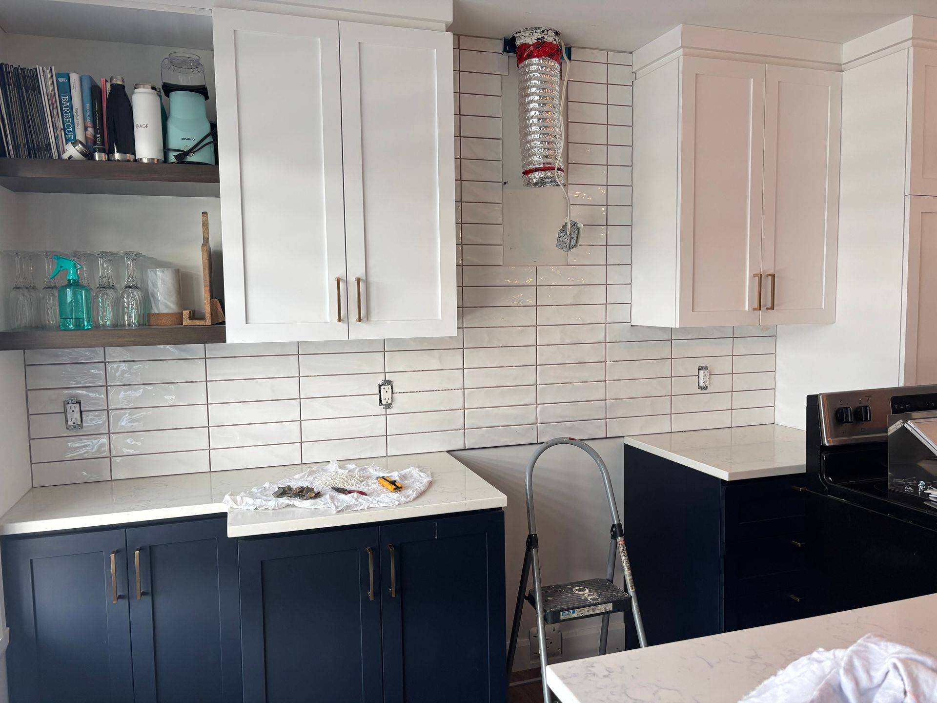 Cuisine avec placards blancs et bleus, comptoirs blancs et crédence carrelée blanche.