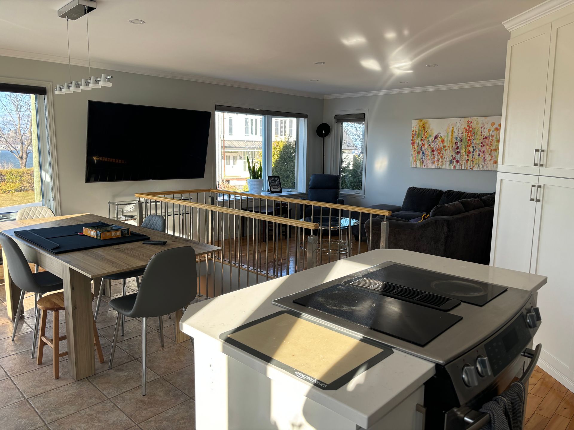 Espace de vie ouvert comprenant un îlot de cuisine, une table à manger et un coin salon avec une grande télévision.