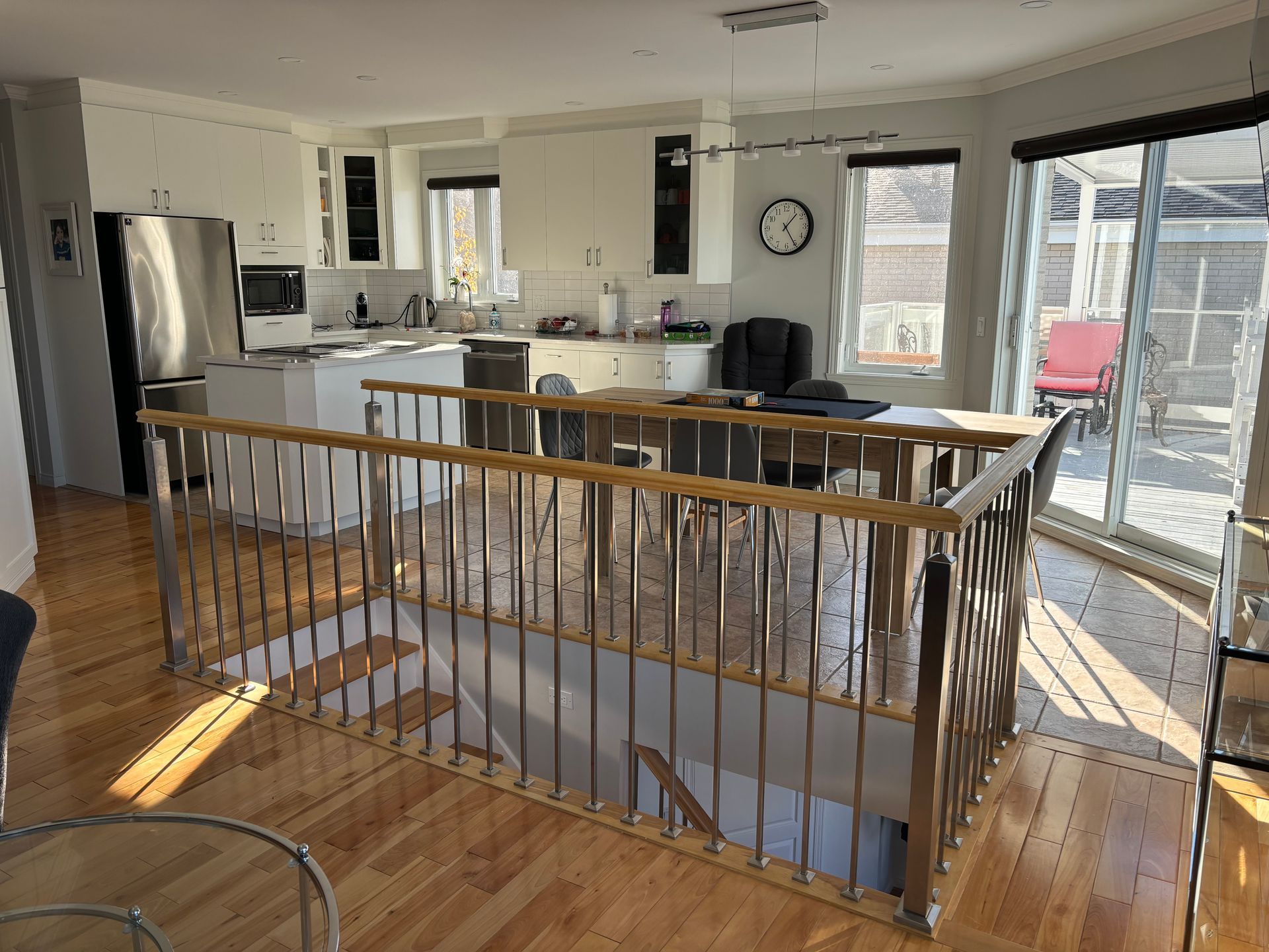 Intérieur avec parquet, escalier, cuisine et coin repas, baigné de lumière naturelle.