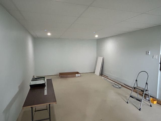 Pièce vide aux murs bleu clair, une table marron et un escabeau.