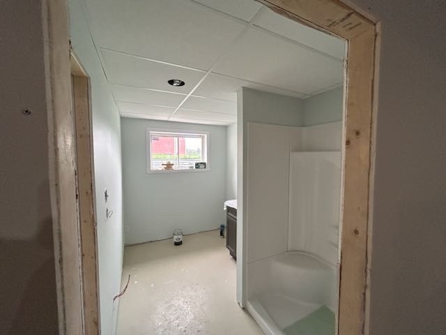 Vue intérieure d'une salle de bains en cours de rénovation ; murs et plafond bleu clair, cabine de douche blanche, cadre de porte non fini.