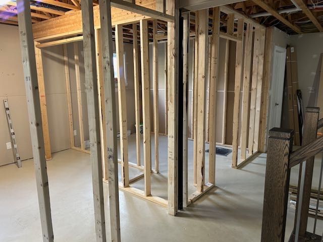 Montants en bois soutenant les murs intérieurs d'un sous-sol. Escalier visible à droite.