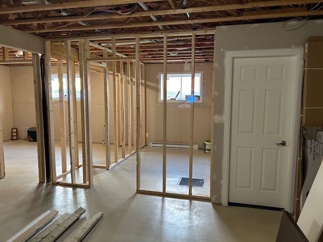 Rénovation du sous-sol : ossature bois pour les murs, espace non aménagé, porte blanche.