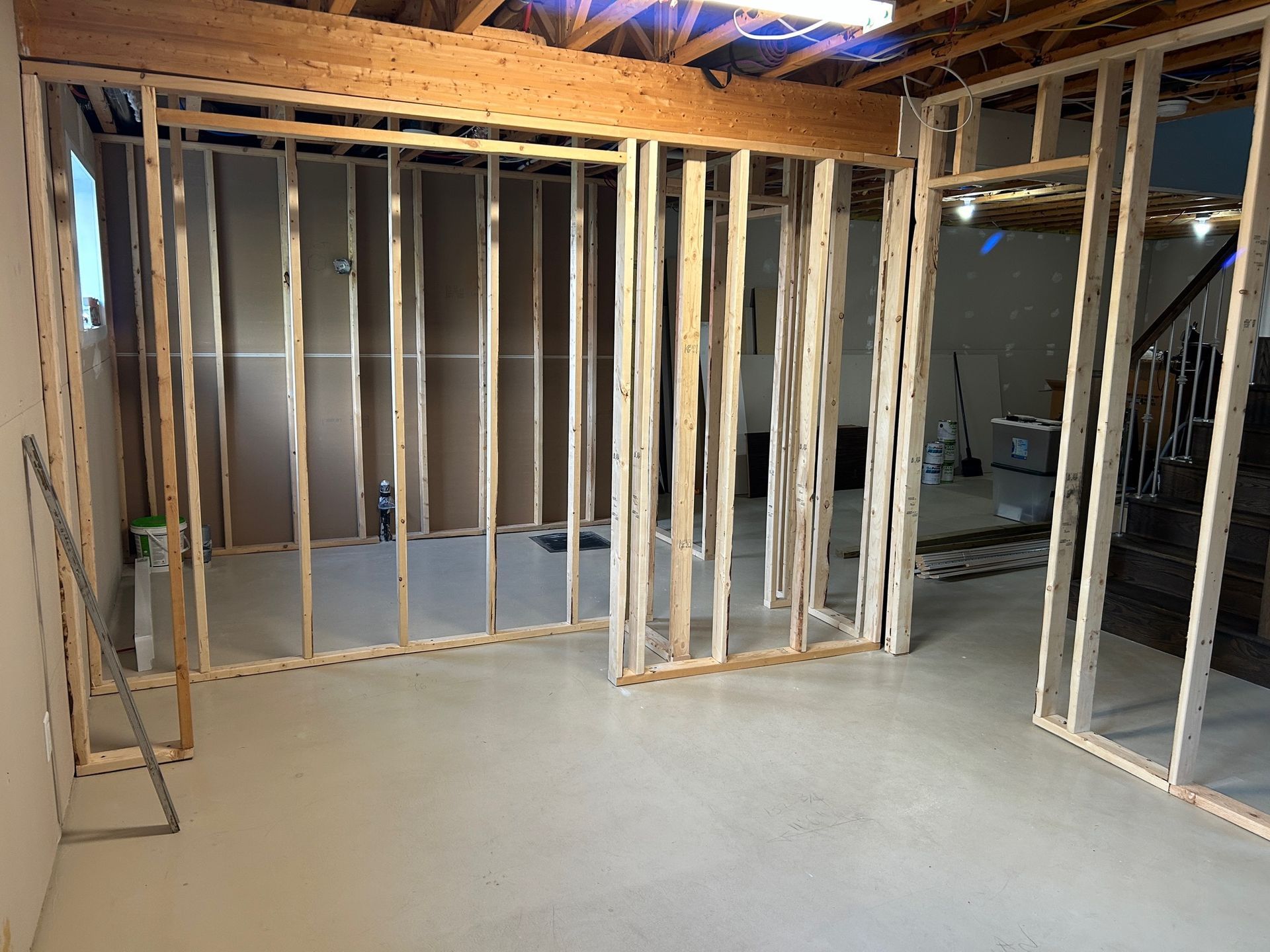 Intérieur d'une pièce en construction avec ossature bois pour les murs et les portes. Sol en béton clair.