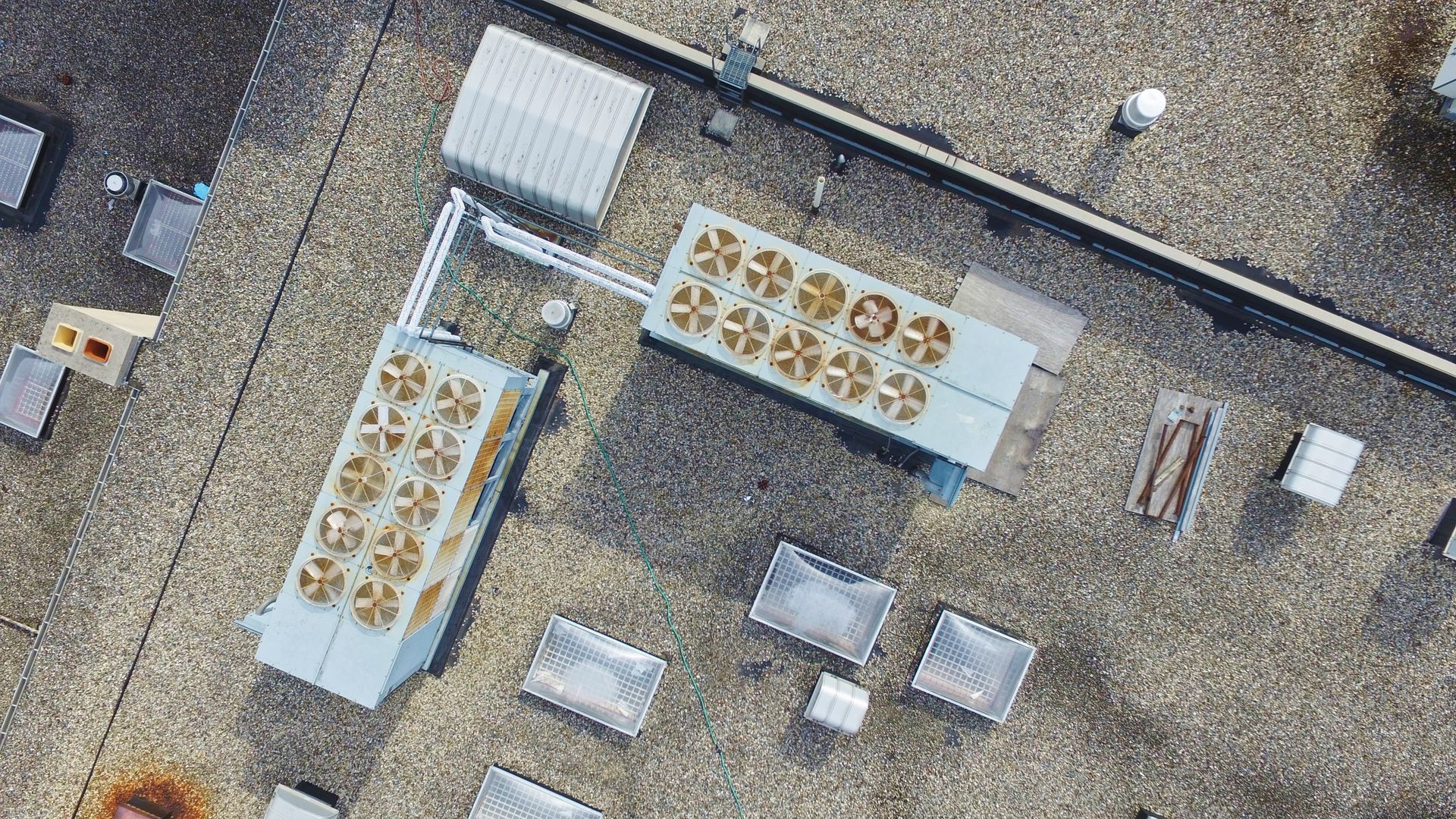 Overhead view of a flat rooftop with multiple HVAC units and other equipment.