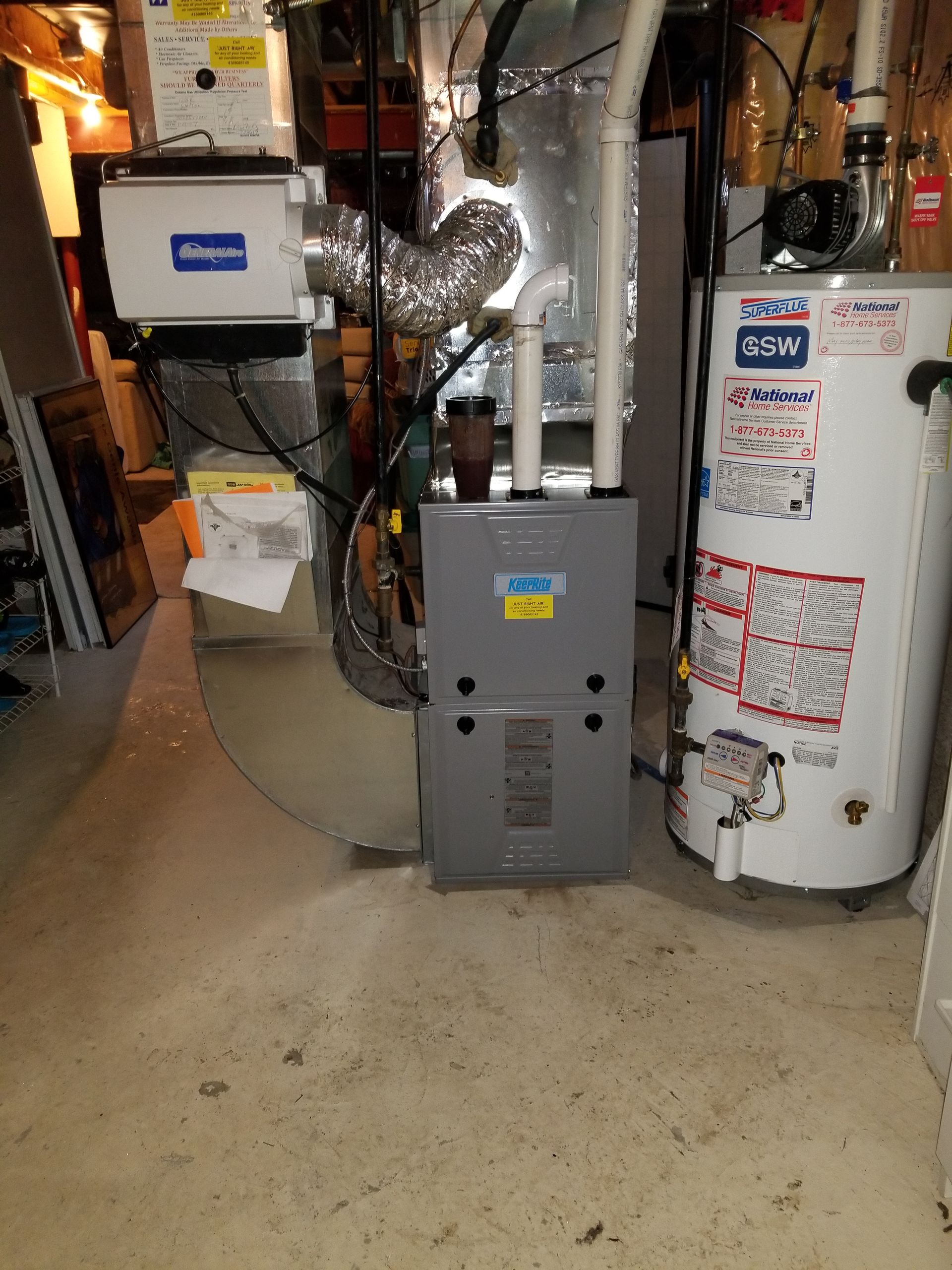 A water heater is sitting next to a furnace in a basement.