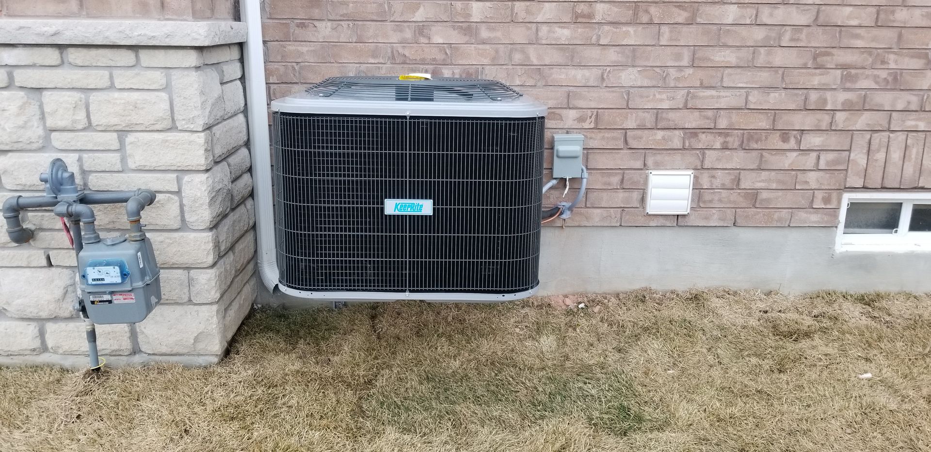a heat pump is mounted on the side of a brick building.
