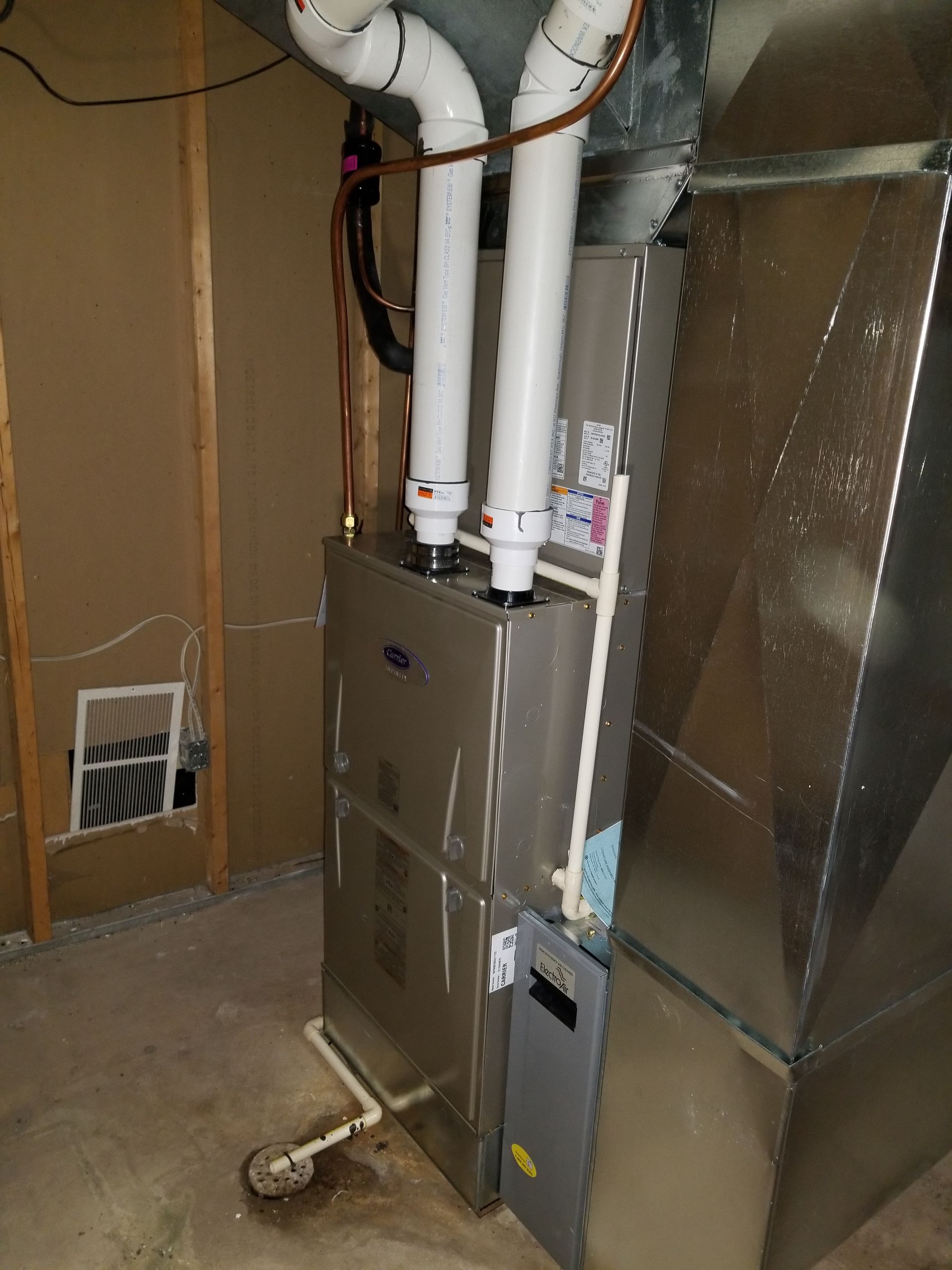 A stainless steel air conditioner is sitting in a basement.
