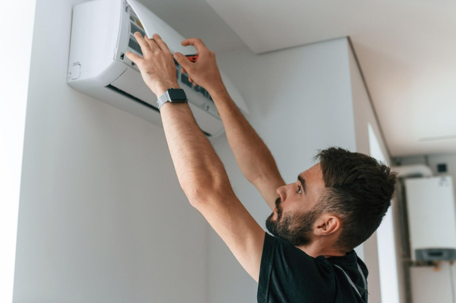 Man cleaning air conditioner filter, white room.
