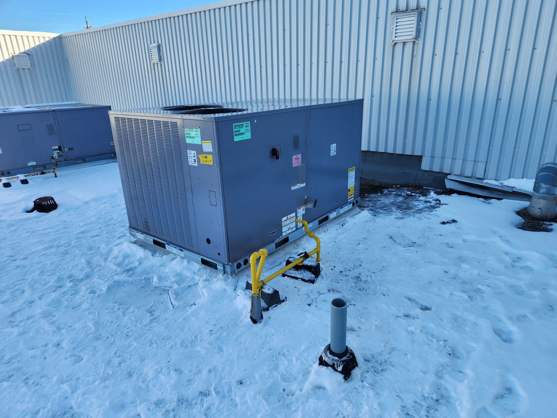 a large air conditioner is sitting in the snow in front of a building .