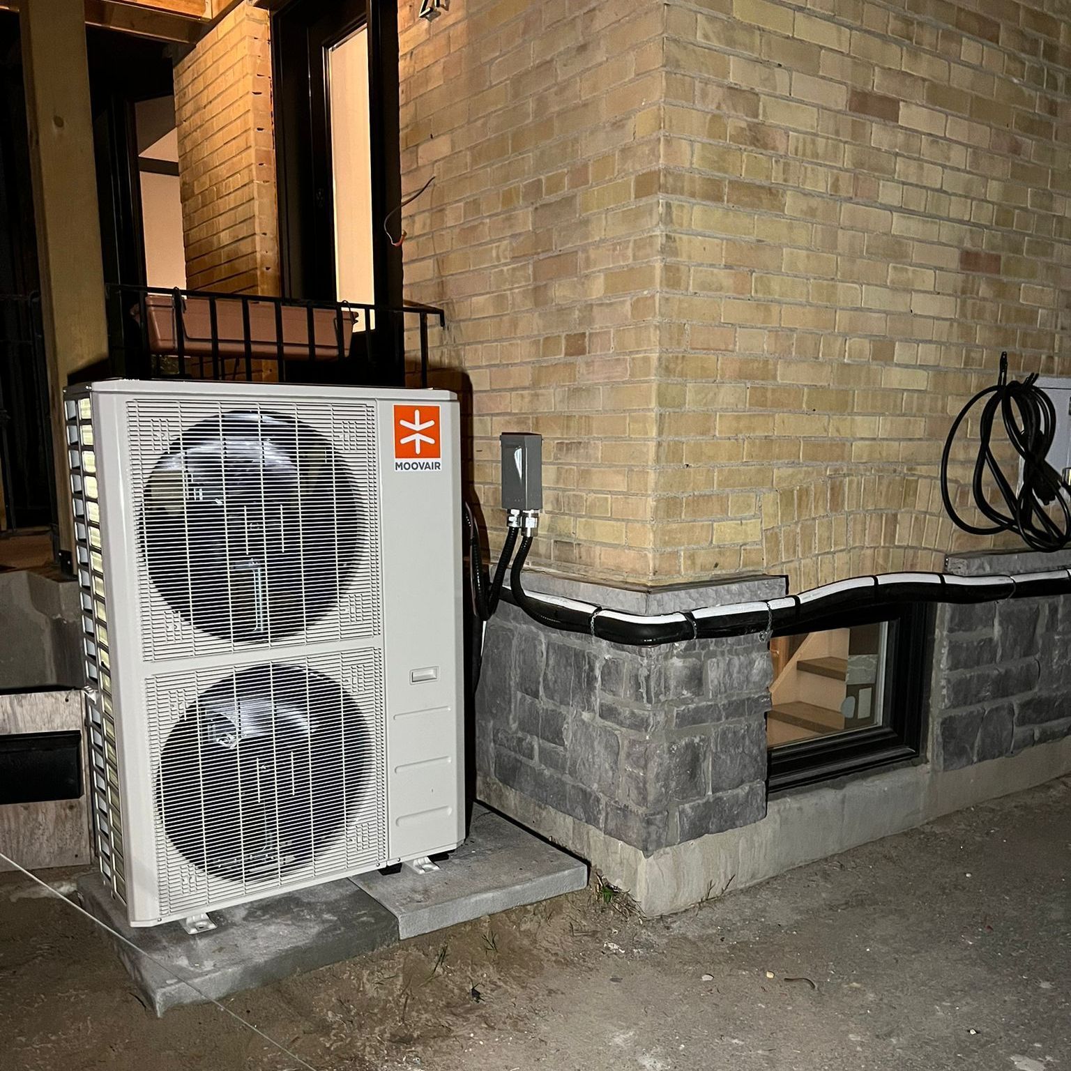 a large heat pump is sitting on the side of a brick building.