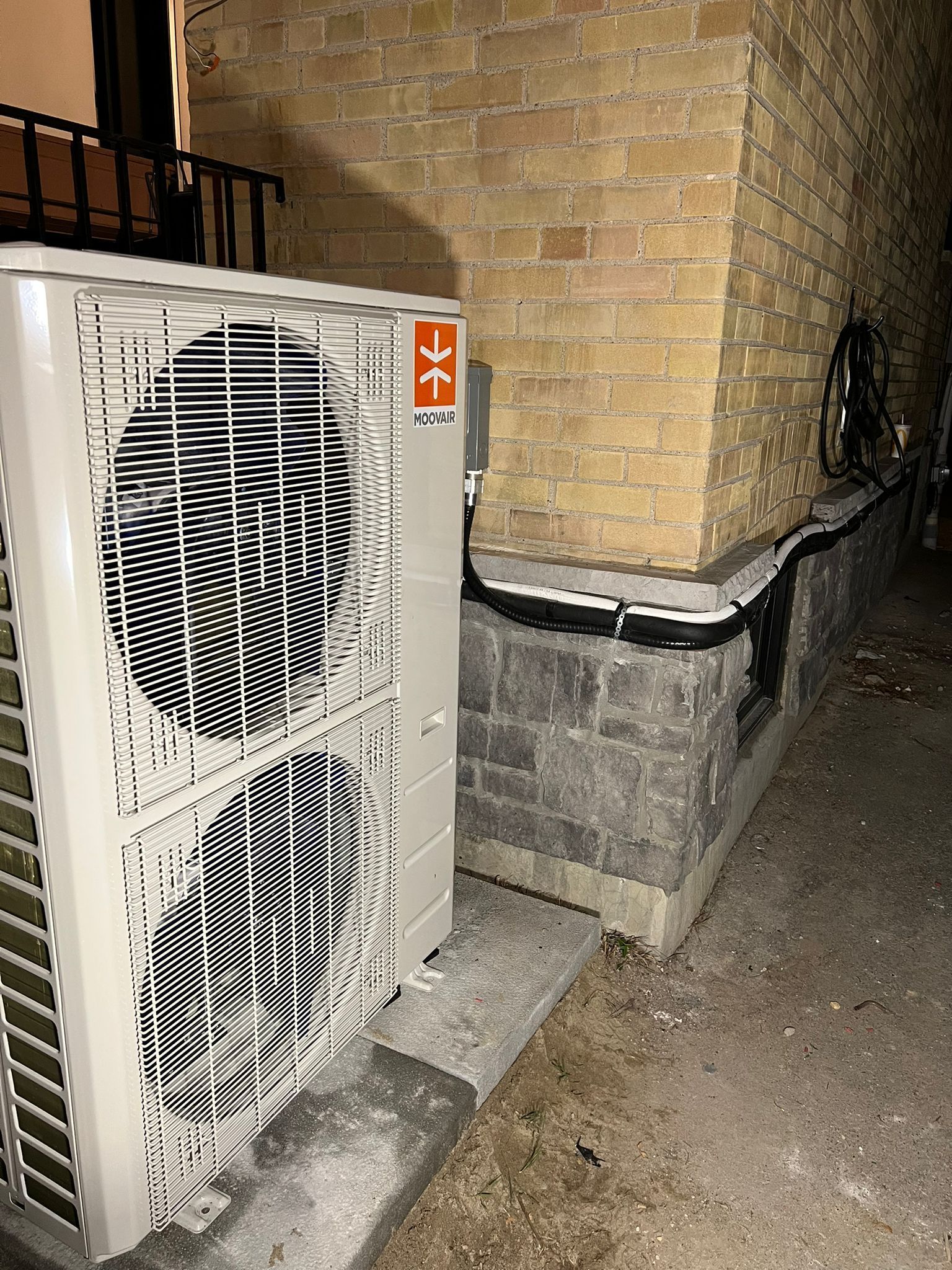 Outdoor heat pump unit next to a brick wall.