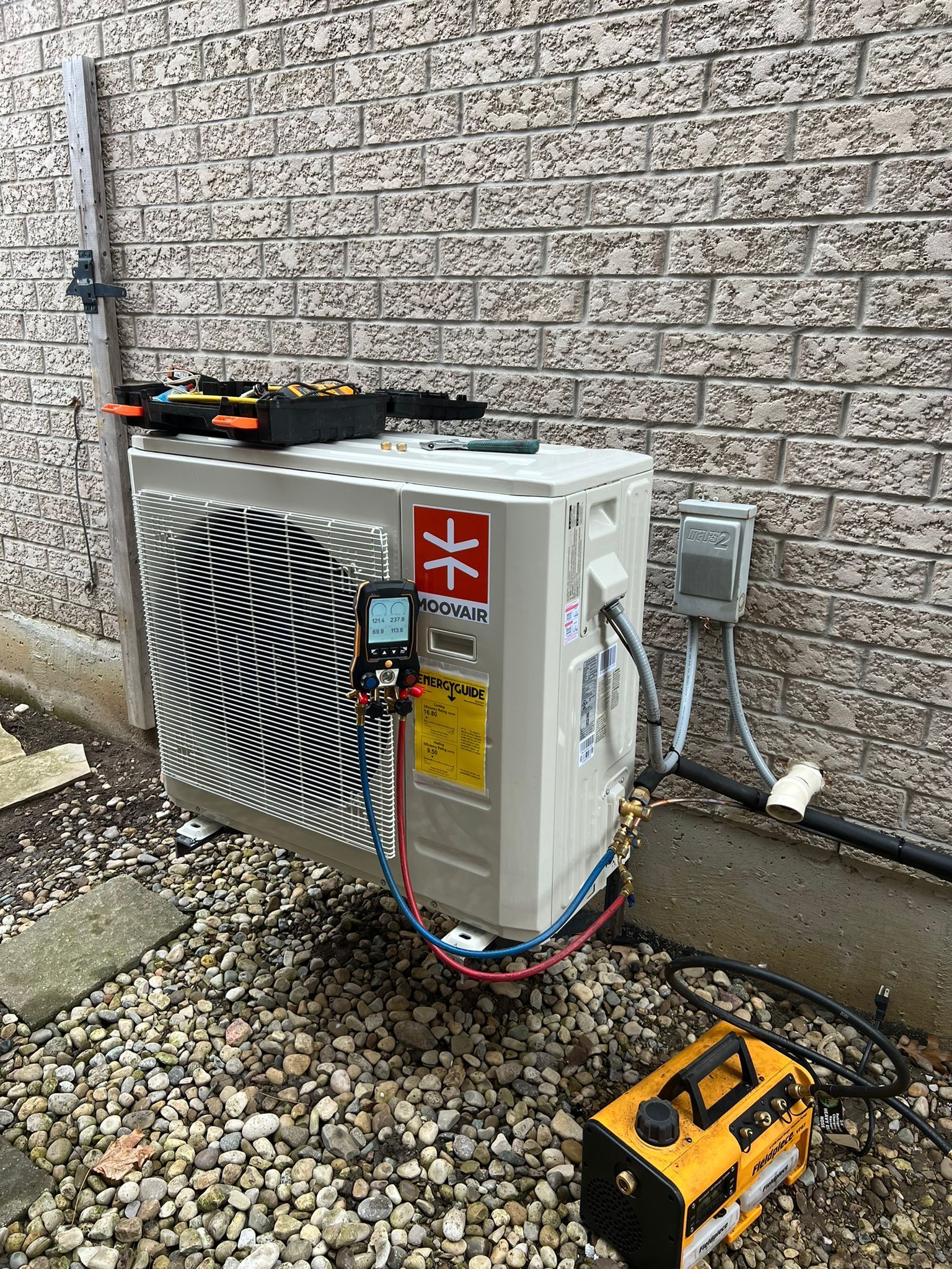 an air conditioner is being installed on the side of a brick building .