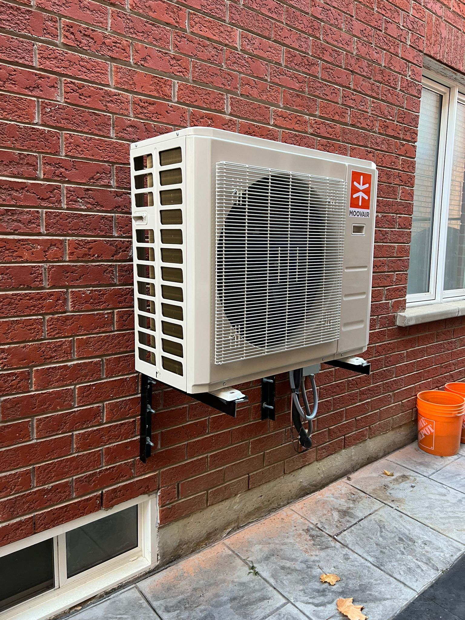 a large air conditioner is mounted on the side of a brick building .