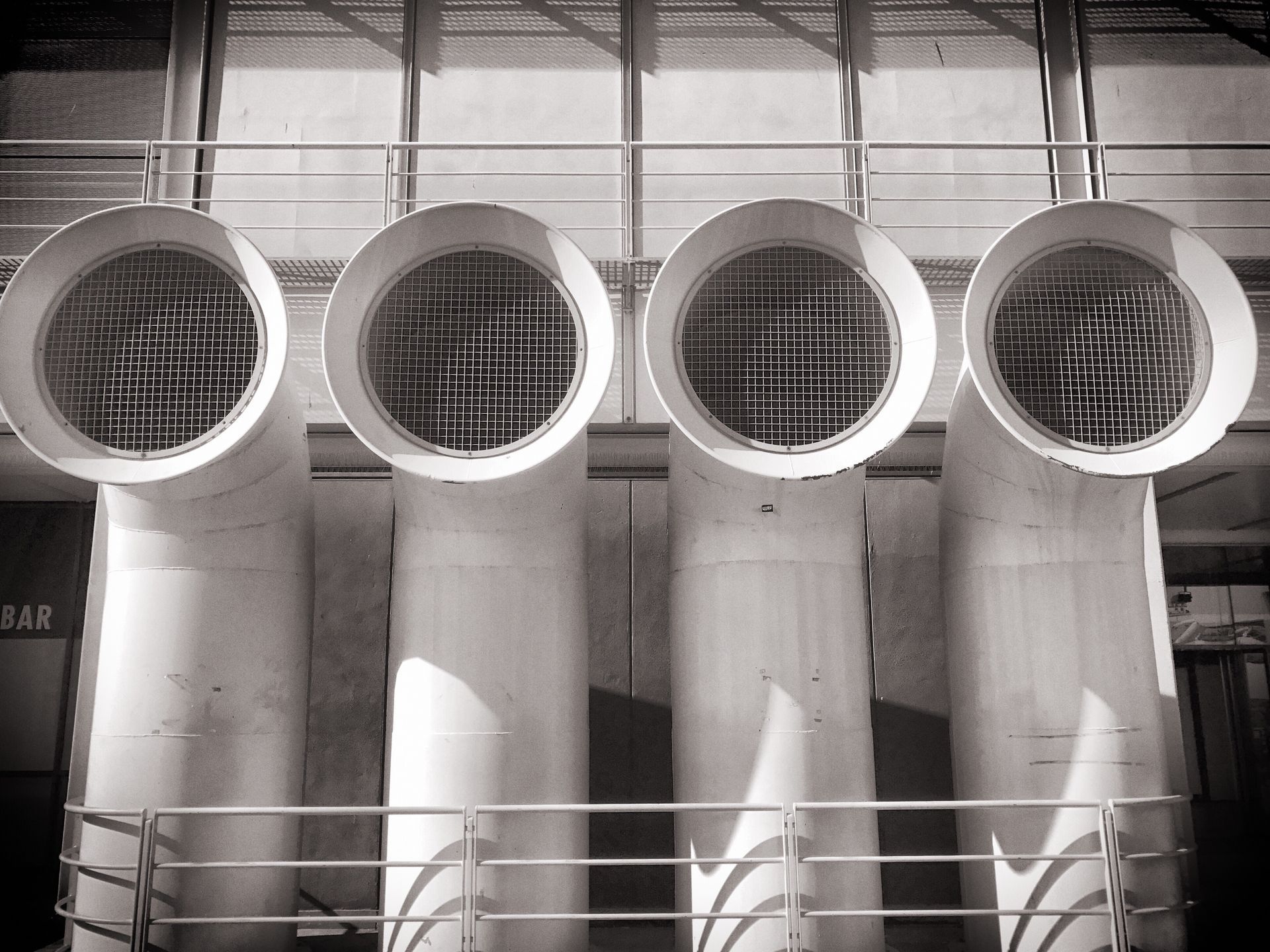 Four large, cylindrical vents with metal grates, possibly for industrial cooling, in black and white.