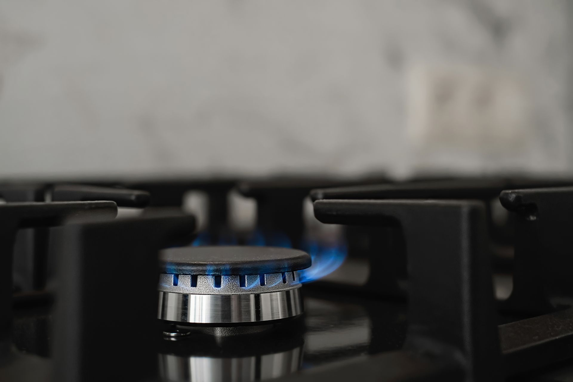 Blue flame burning on a black gas stove burner.