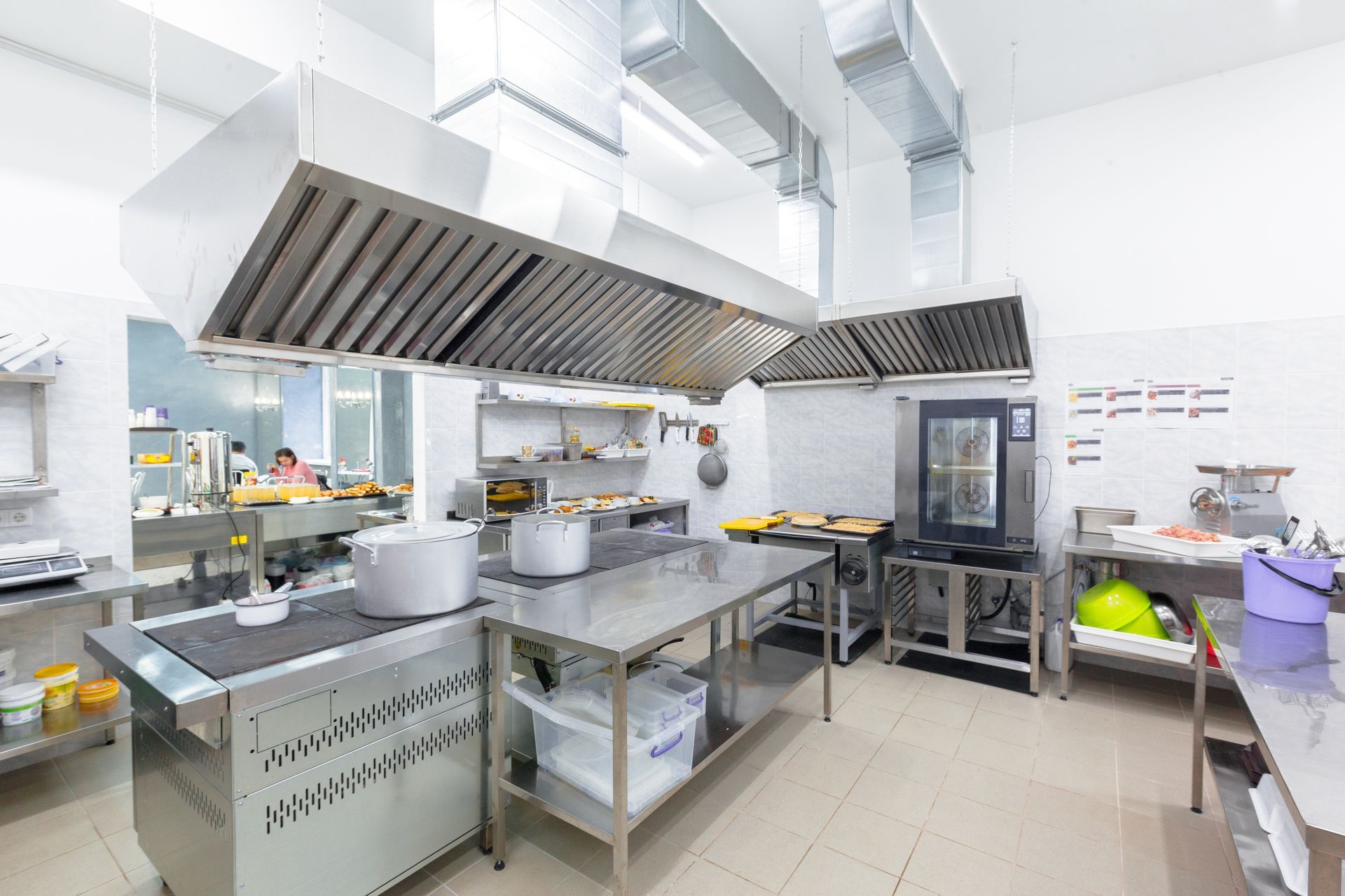 Commercial kitchen with stainless steel equipment and range hoods.
